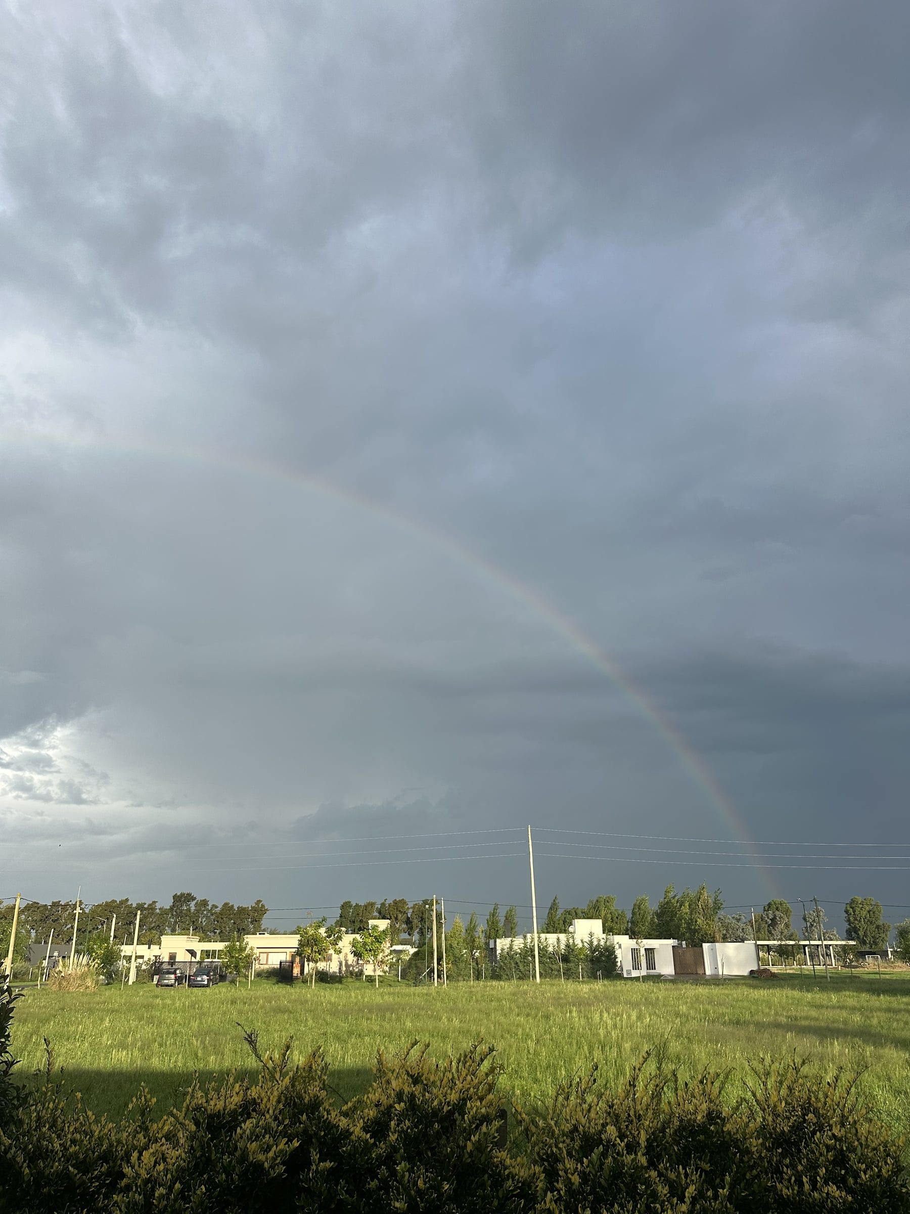Casas del barrio La Cañada con un arcoíris sobre el campo